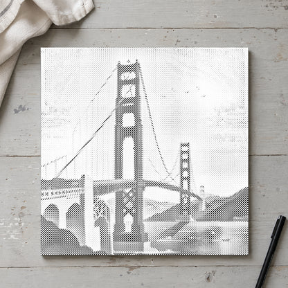 Prickmålningen “Golden Gate Bridge”, sedd ovanifrån på ett arbetsbord i mjukt dagsljus.